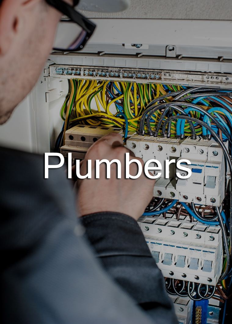 A tradesman working on pipework and wiring